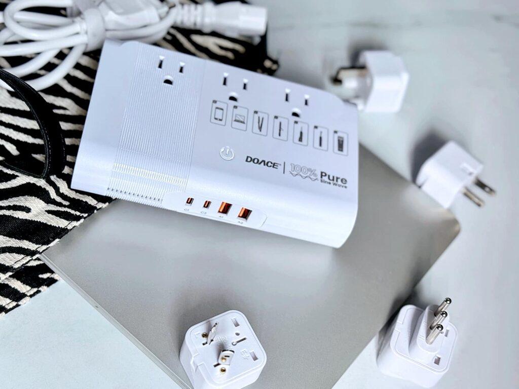 Travel voltage converter with AC outlets, USB charging ports, and plug adapters for different countries.