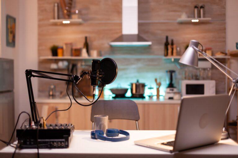 Home creator setup with a laptop, microphone, audio mixer, and lighting, illustrating the preparation and delivery of livestream or podcast announcements.